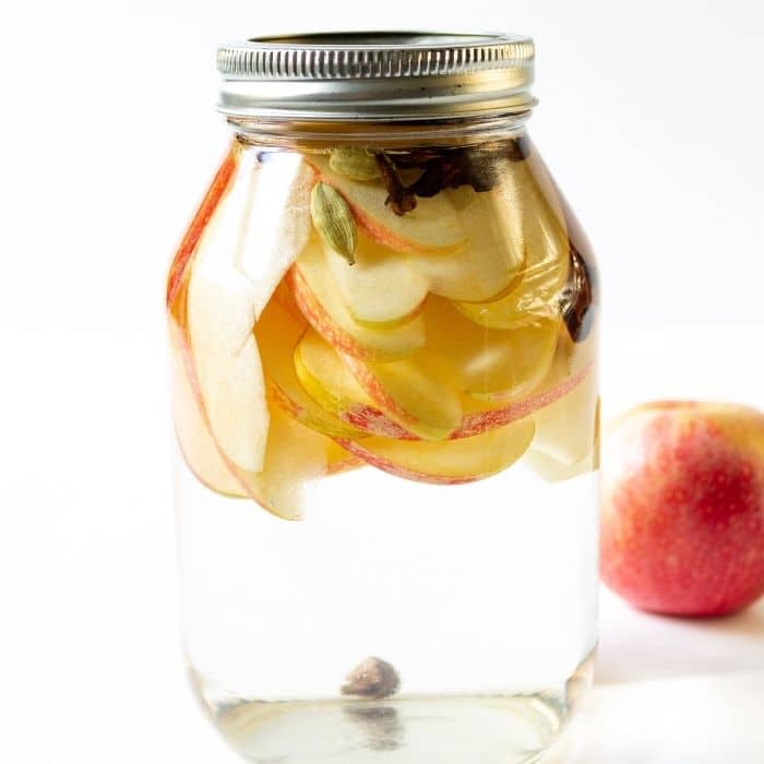 mason jar with vodka and apples and warm fall spices in it 