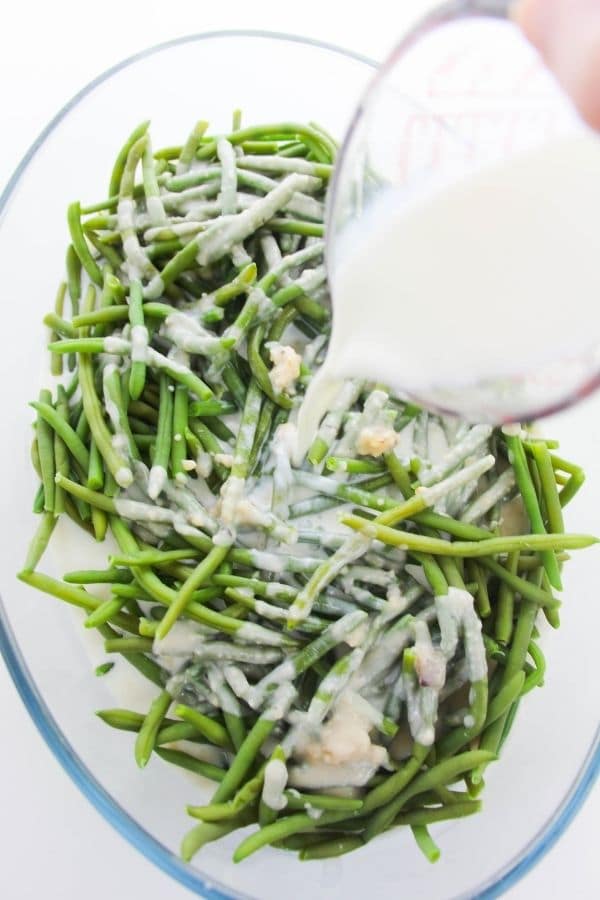 pouring milk into green bean casserole mixture 