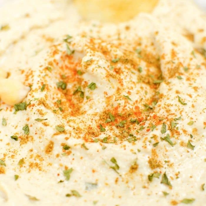 closeup of a bowl of hummus with spices on top 