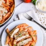 vokda pasta with chicken on a table with items all around it