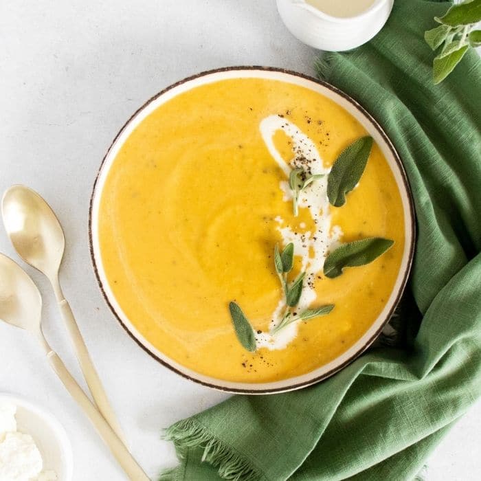 butternut squash soup with cream and fresh herbs on top 