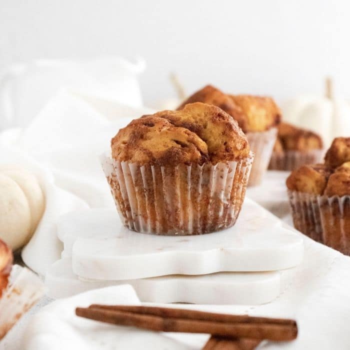 muffin on table with cinnamon sticks by it 