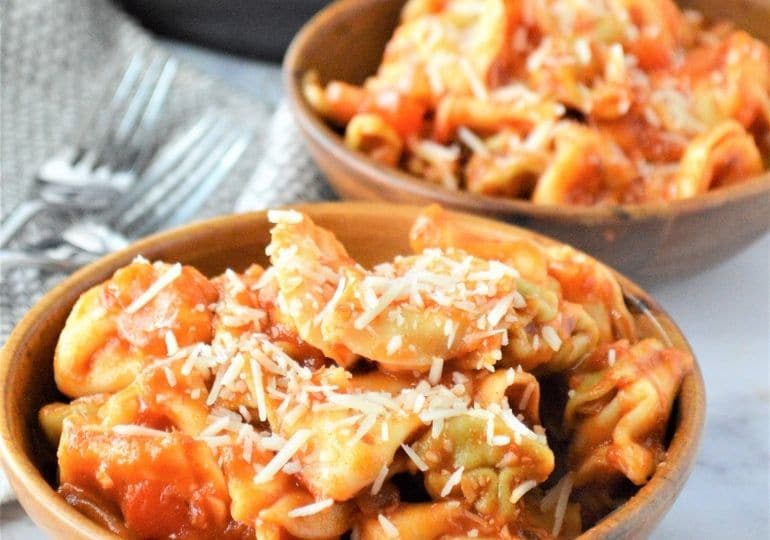 two bowls of pasta with cheese grated on top