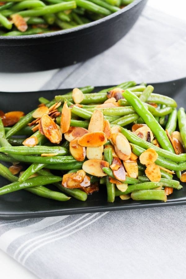 green beans on a plate with pan behind it 