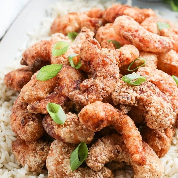 buttermilk fried shrimp on a platter with green onion slices 