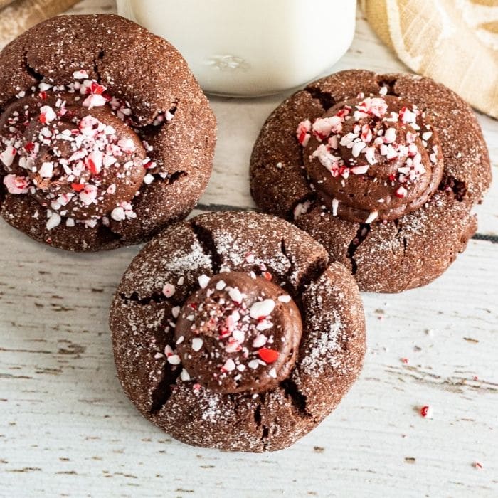 mint thumbprint cookies on table with milk behind it 