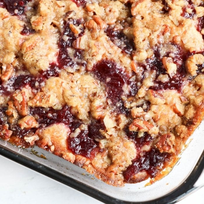 cranberry coffee cake in a glass container on table 