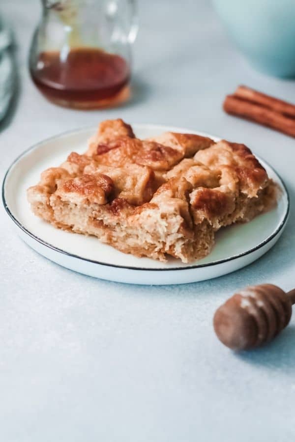 eggnog french toast bake on a plate with maple syrup behind it 