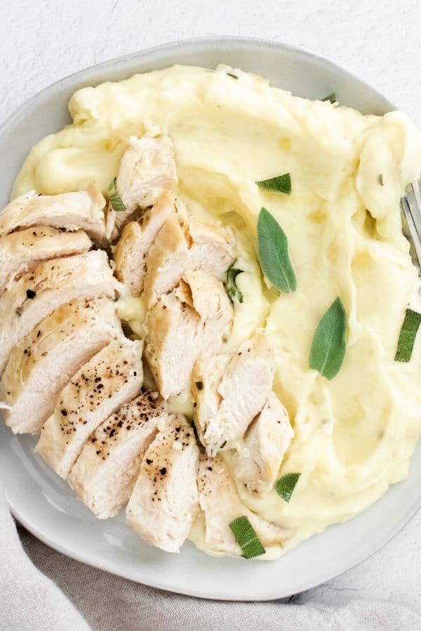 bowl loaded with mashed ptoatoes and sliced chicken breast on top