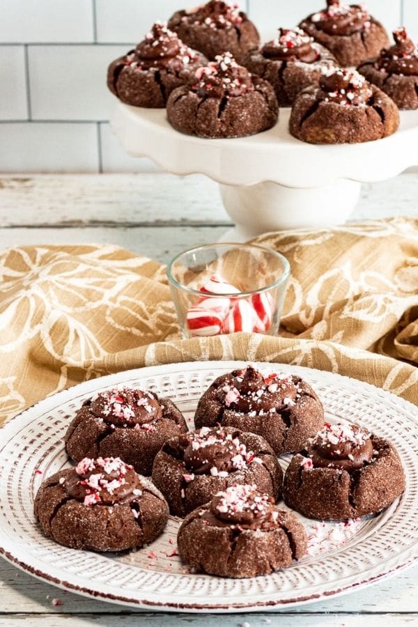 peppermint thumbprints on a plate and then a cake stand with more behind it cookies