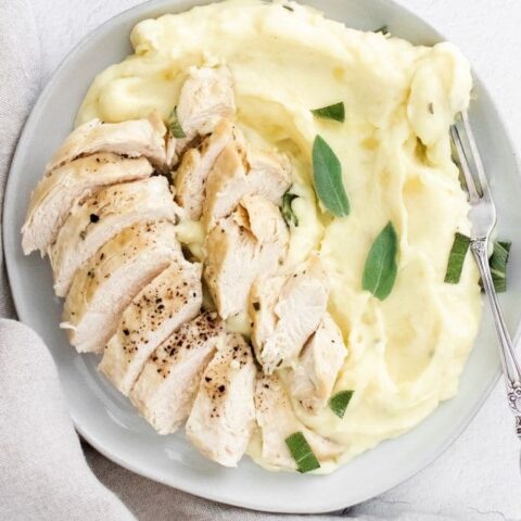potatoes and chicken on a plate with sage on top