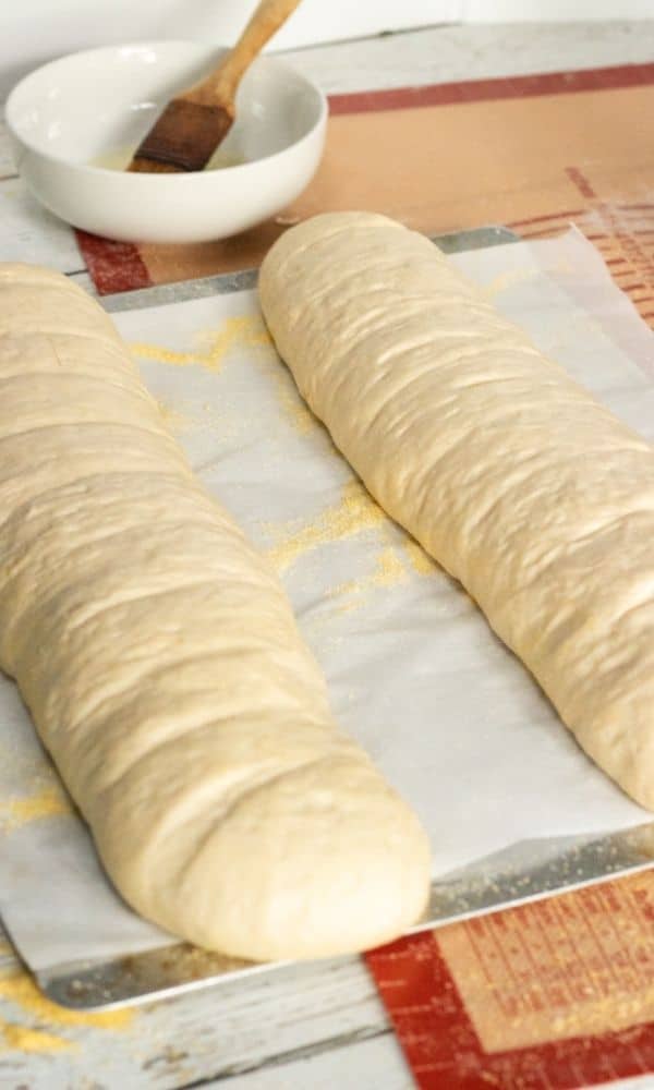 french bread with slits and buttered on baking sheet