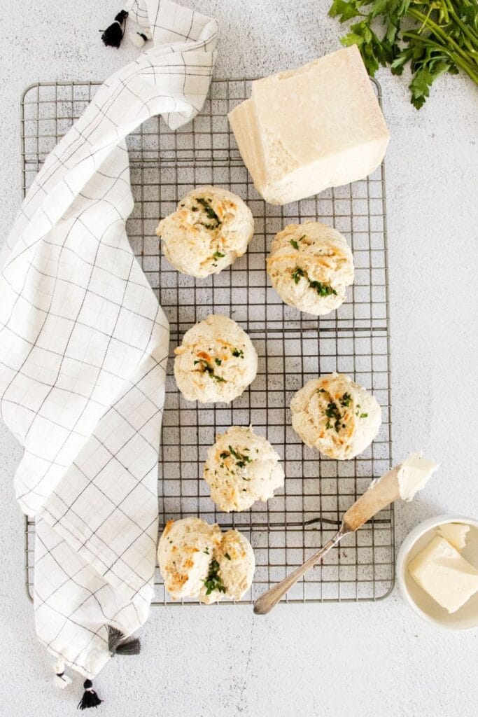 cooking rack with biscuits on it and butter and towel beside it 