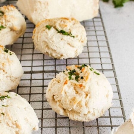 buttermilk parmesan garlic biscuits on cooling rack with knife with butter on it