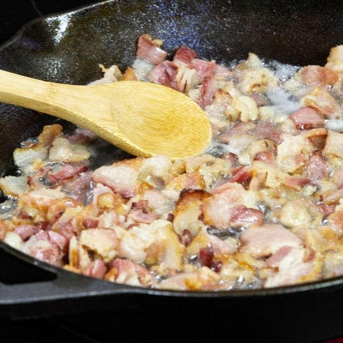 pan with diced cabbage being fried with wooden spoon