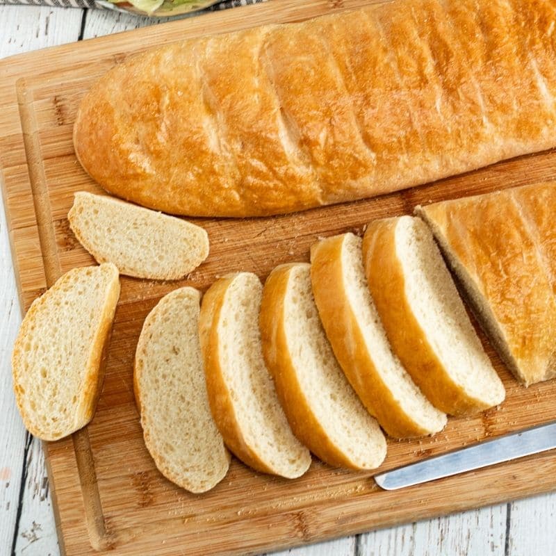 two french breads on a wood cutting board on table 