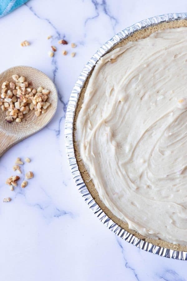 peanut butter pie on marble counter with nuts by it 