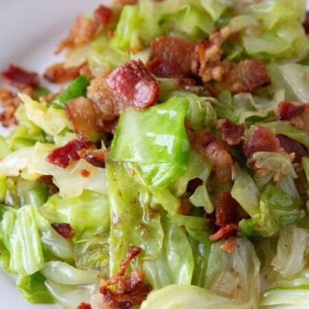 cabbage and bacon dish on a white plate on table