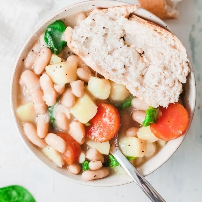 white bean soup in a bowl with slice of bread