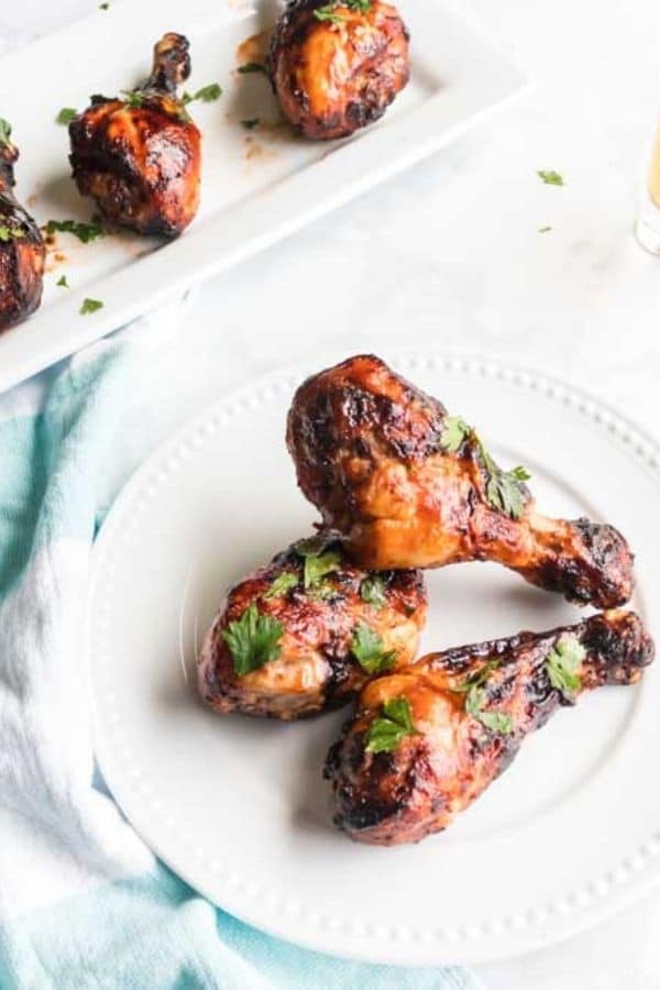 chicken drumsticks on plate with more on a platter behind it 