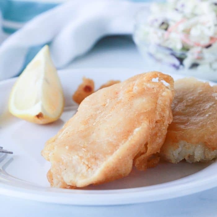 best beer batter fish on plate with lemon wedge