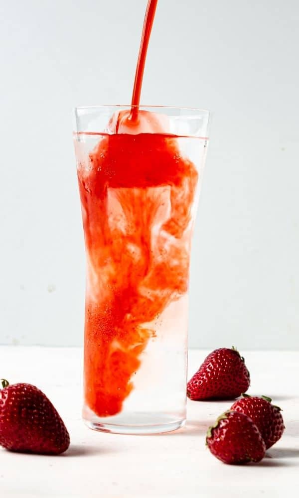 strawberry syrup pouring into water 