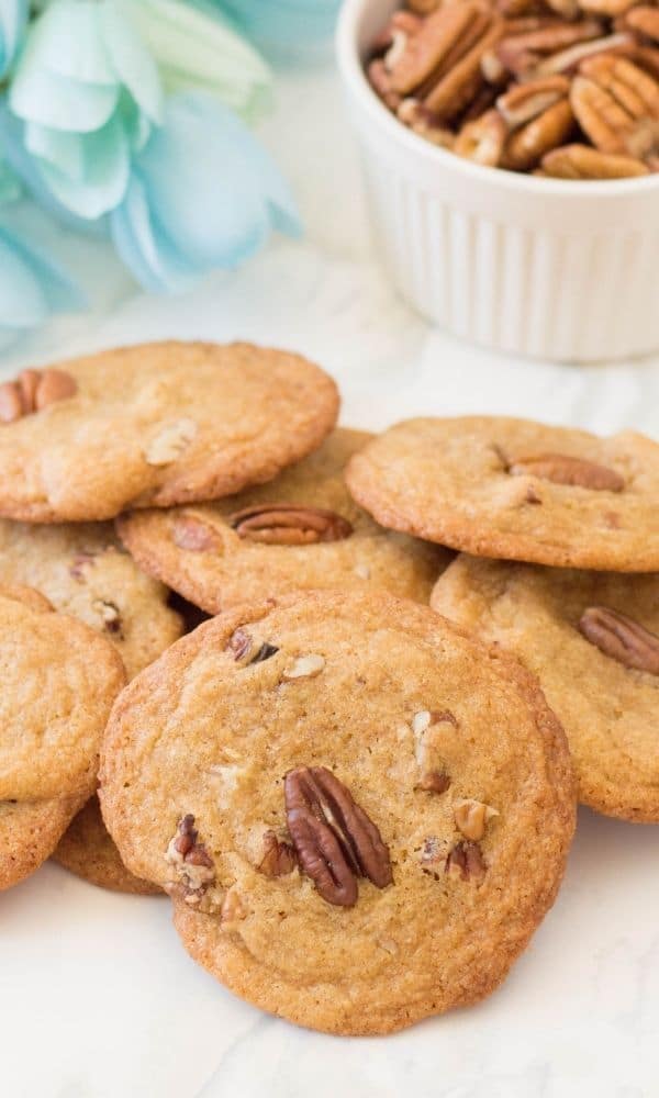 cookies stacked on top of each other on table with bowl of nuts behind it 