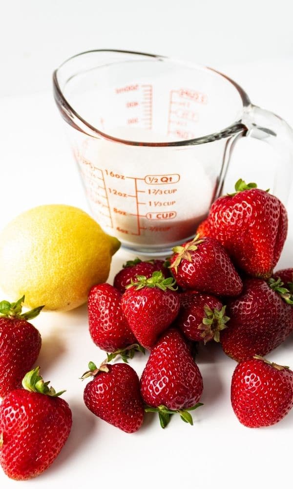 strawberries, lemon and sugar sitting on white table