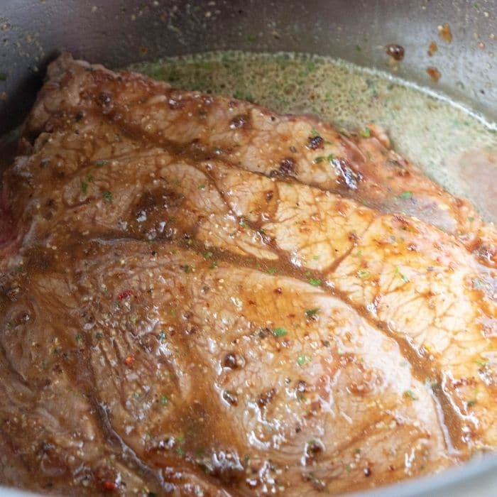 raw roast with seasoning and liquid to be cooked in pot