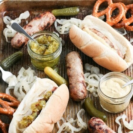 bratwurst on buns, and on cooking sheet with condiments around it