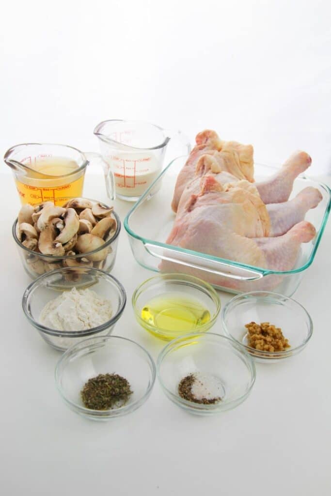 ingredients for chicken and mushrooms on a white table 