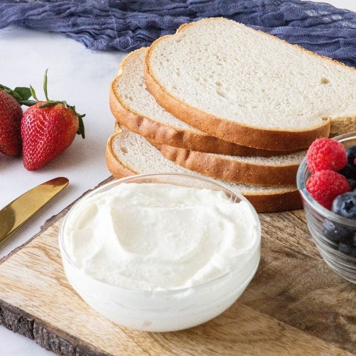 creamy cream cheese in bowl and bread and berries beside it 