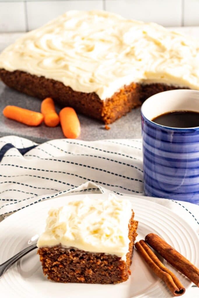 moist carrot cake bars on plate with coffee behind it 