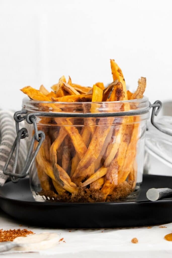 sweet potato fries in a jar on a black platter on table 