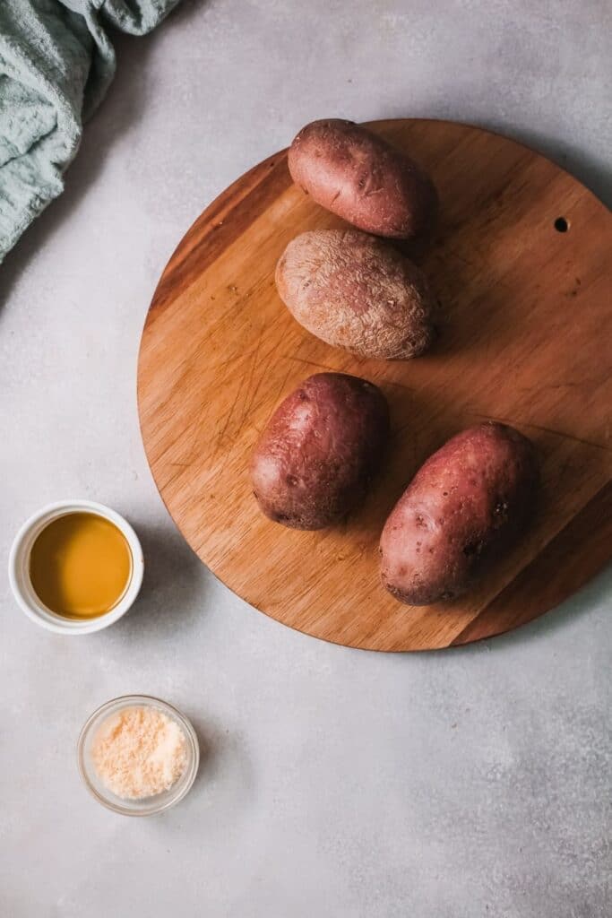 potatoes on a cutting board with oil and parmesan cheese