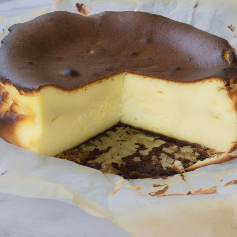 sliced burnt cheesecake  with parchment paper around it 