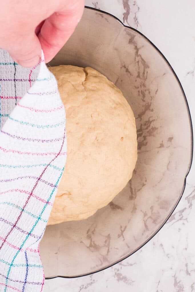 donut dough in a bowl with towel over it