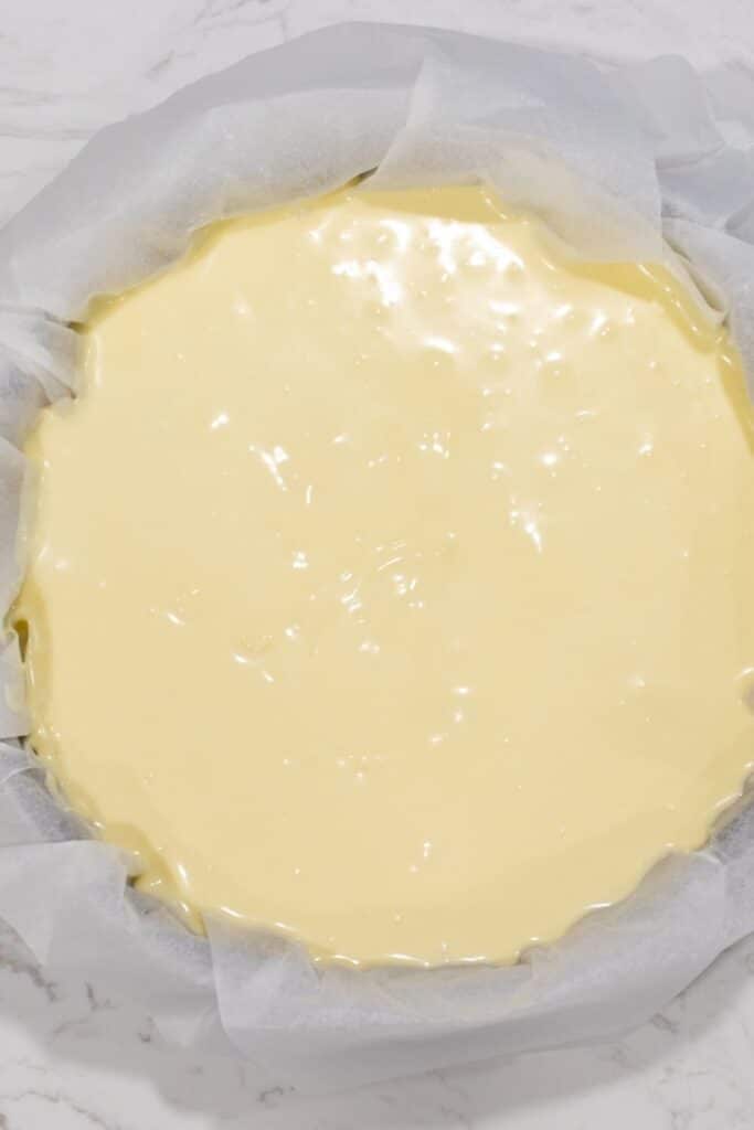 cheesecake batter in a pan with parchment paper 