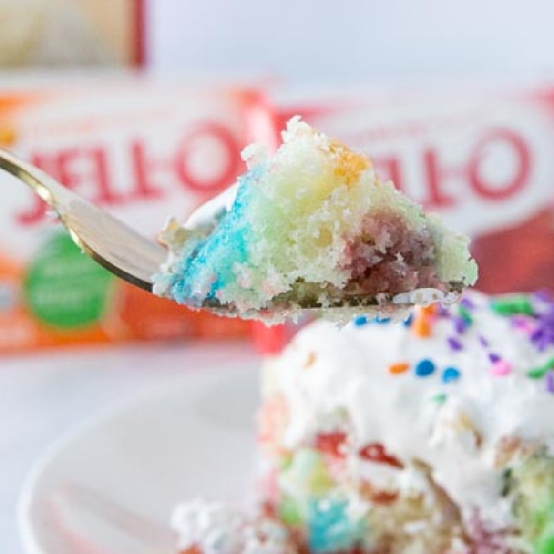 Jello poke cake on a plate with fork full of cake