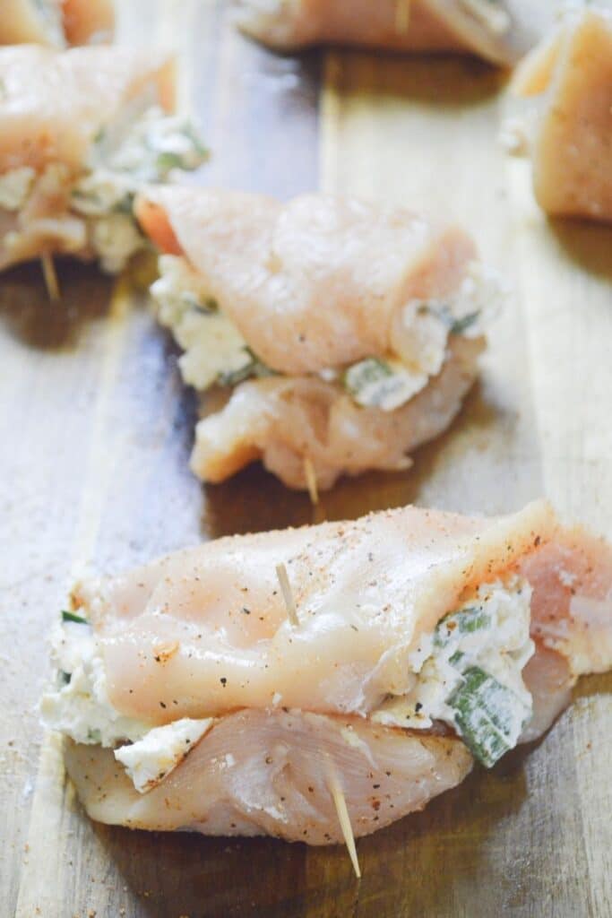 cream cheese stuffed chicken on wooden cutting board 