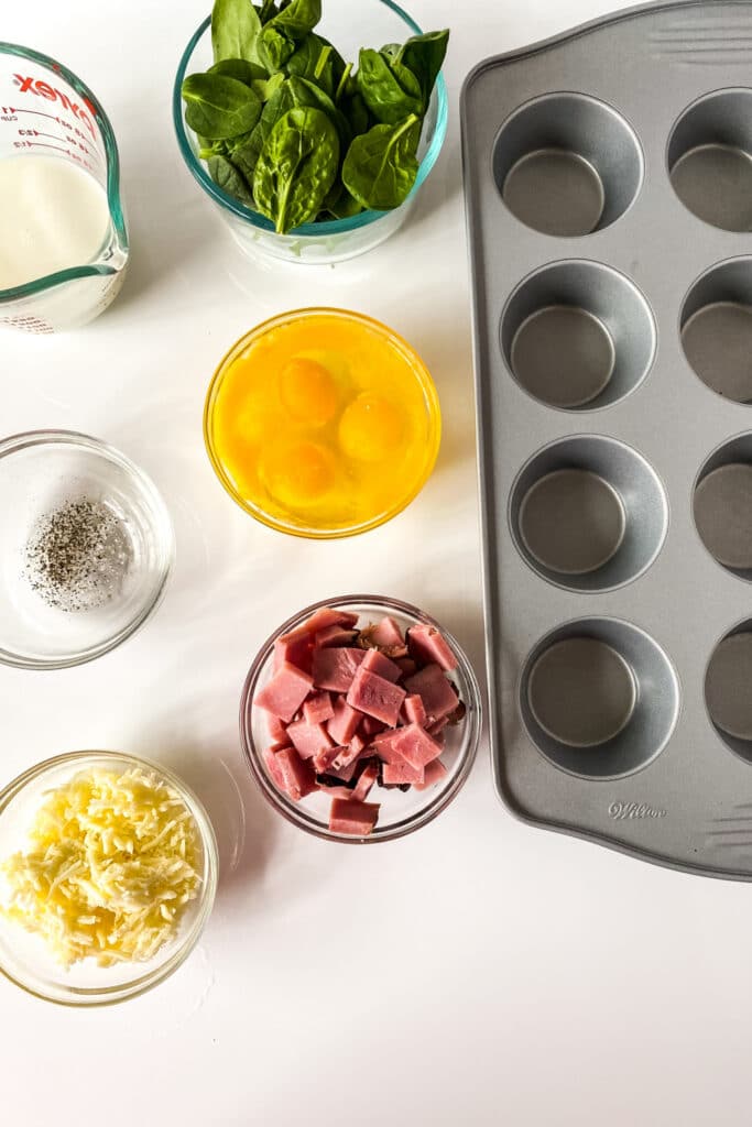 ingredients for egg spinach frittatas on counter with muffin tin by it 