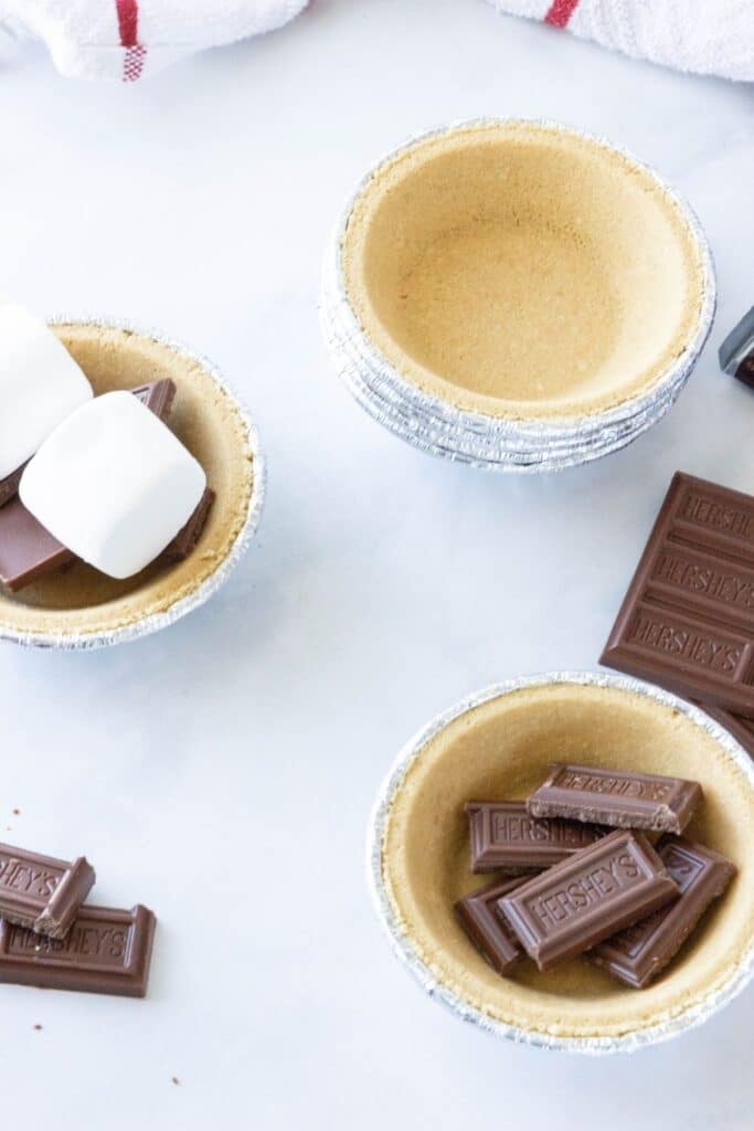 smores mini dessert pies on table with chocolate by it 