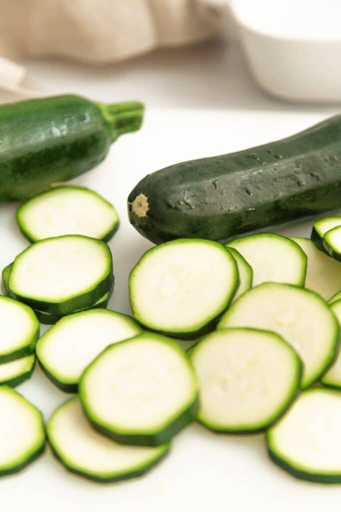 zucchini shredded on counter with whole ones behind it 