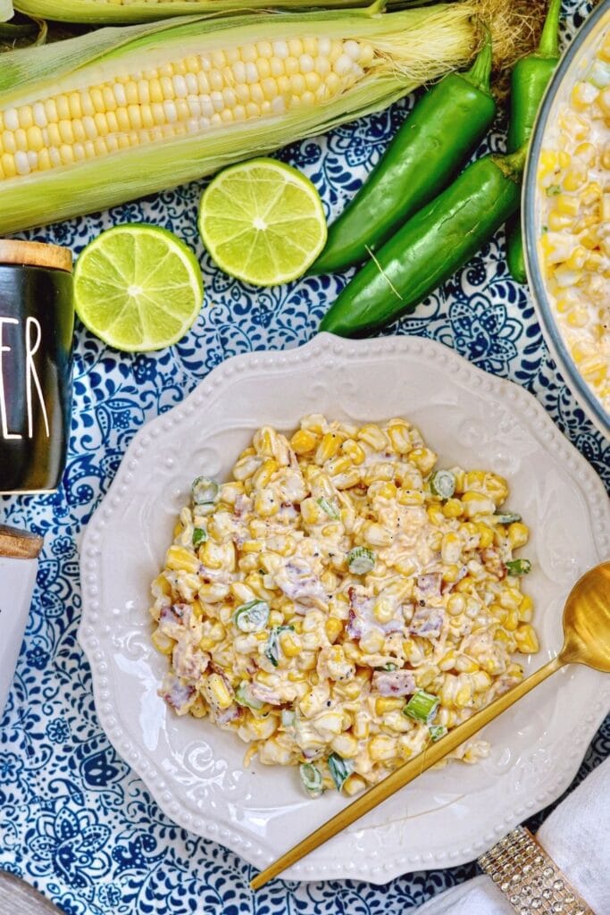 cold corn salad in a bowl with vegetables around it 