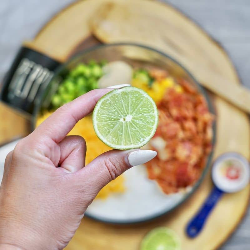 squeezing lime into a corn salad mixture 