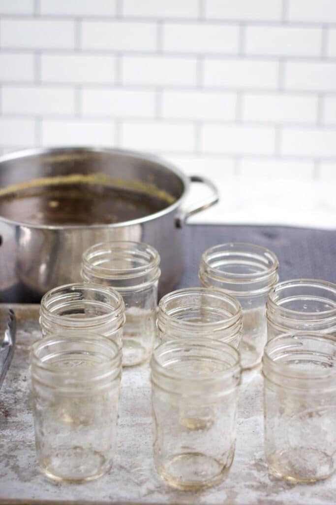canning jar placed on table with pot of jelly behind it