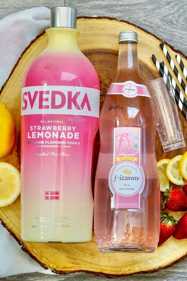 strawberry lemonade vodka and cocktail supplies on wooden board