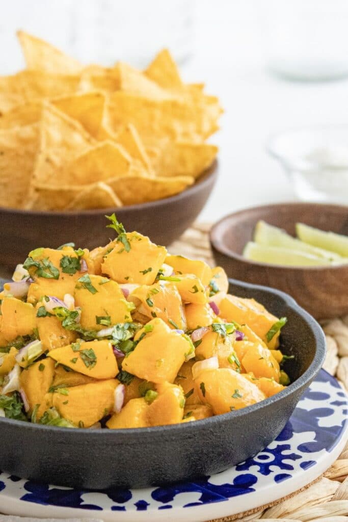 mango dish in pan with limes and chips by it