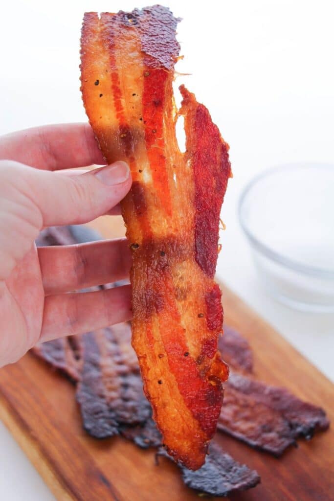 holding a piece of candied bacon