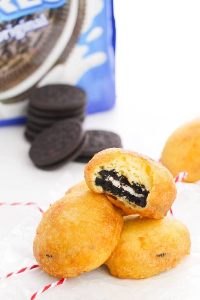 stack of deep fried Oreo cookies on table with Oreo container behind it 